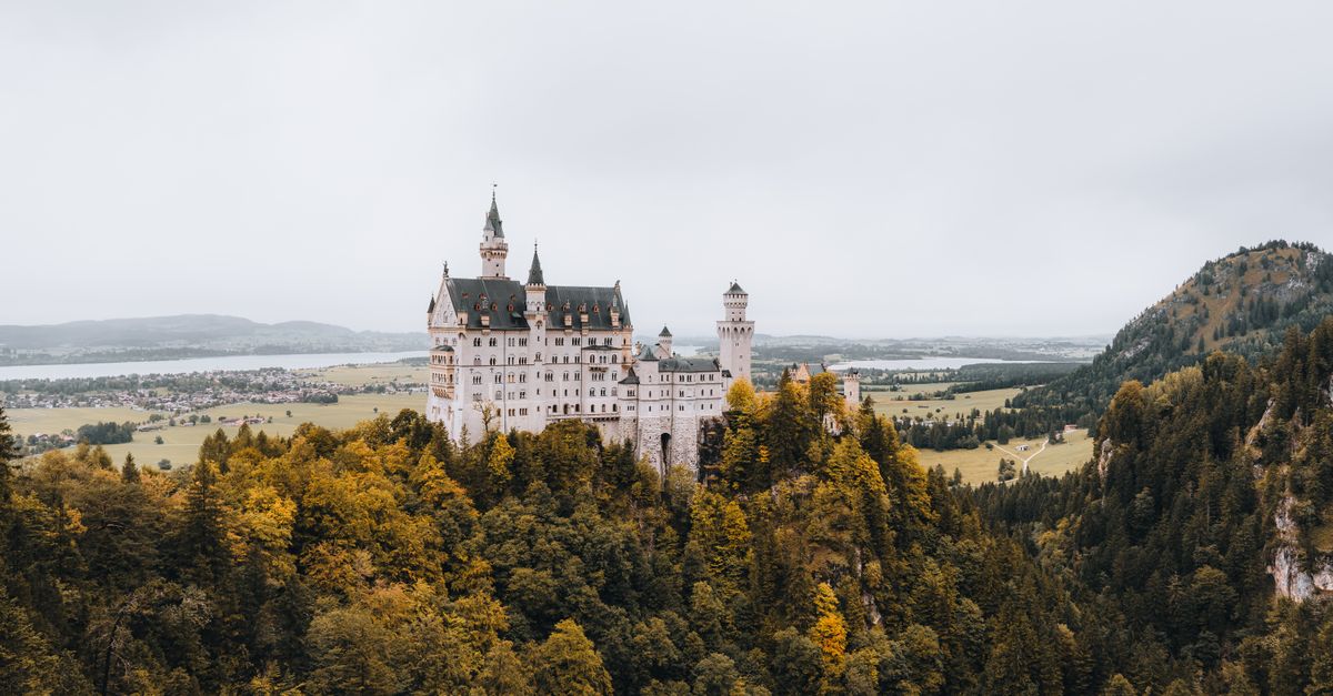 Stunning aerial view of Neuschwanstein Castle amid autumn foliage in Bavaria, Germany.